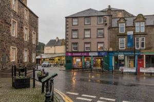 uma rua da cidade com edifícios em dias chuvosos em Towerknowe em Hawick