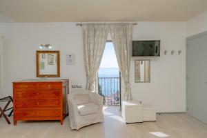 um quarto com uma cómoda, uma cadeira e uma janela em Il Paradiso sul Mare Apartment em Scala