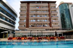 a hotel with tables and chairs in front of a building at CLUB BAYAR BEACH HOTEL in Alanya