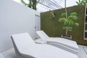2 sillas blancas y una planta en el balcón en The Lavana Seminyak Loft 360 - 1 Bedroom Villa with Private Pool, en Seminyak