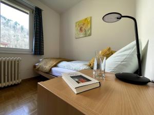 a room with a desk with a lamp and a bed at Zentrum Elisabeth in Walchwil