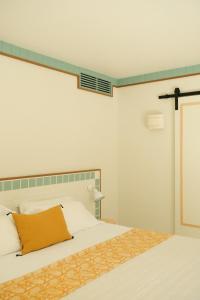 a bedroom with a bed with a yellow pillow on it at Hotel des Dunes in Cap-Ferret