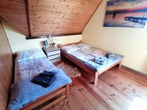two beds in a room with wooden floors at Heniowy Domek in Ogonki