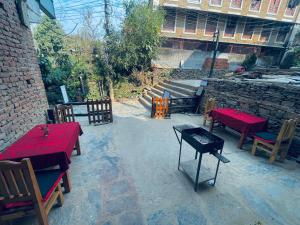 patio ze stołami i krzesłami oraz ceglany budynek w obiekcie Pasne Aajako Hotel w mieście Bandipur
