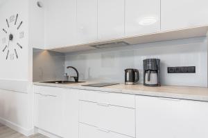 a kitchen with white cabinets and a counter top at Modern Apartaments Armii Krajowej in Świnoujście by Rent like home in Świnoujście