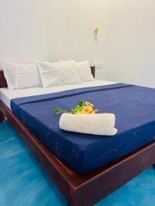 Una cama azul con una toalla encima. en Baywatch Arugambay, en Arugam Bay