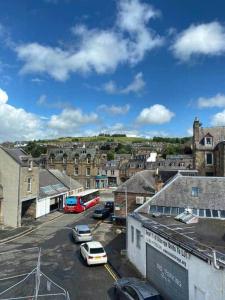 a city with cars parked in a parking lot at Town Centre Apartment in Hawick