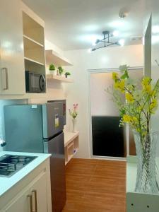 Apartment-Serviced & Condo Free pool in Quezon City by Mi'Casa في مانيلا: مطبخ مع ثلاجة و مزهرية مع الزهور