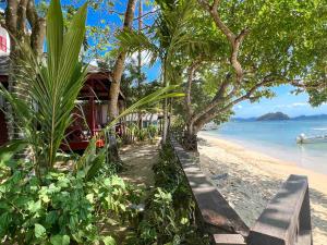 a beach with a bench and trees and the water at Doublegem Beach Resort and Hotel in El Nido