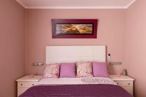 um quarto com uma cama com almofadas roxas e cor-de-rosa em Martiánez Playa: Coastal Location em Puerto de la Cruz