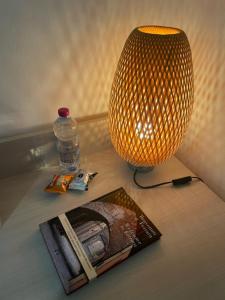 a table with a lamp and a book and a bottle at Stella De' Tolomei in Ferrara