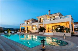 a large house with a swimming pool in front of it at Lavish Athens Pool Villa - Indulge in Luxury in Anavyssos