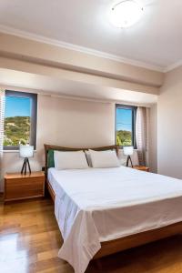a bedroom with a large bed and two windows at Lavish Athens Pool Villa - Indulge in Luxury in Anavyssos