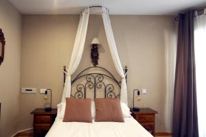 a bedroom with a white bed with a canopy at Hotel Arco San Vicente in Avila