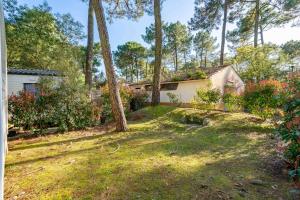 une maison dans une cour avec des arbres et de l'herbe dans l'établissement Mobil home La Palmyre, aux Mathes
