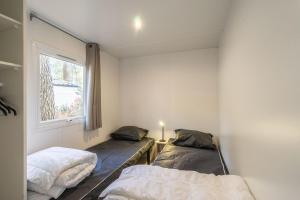 two beds in a room with a window at Mobil home La Palmyre in Les Mathes