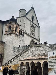 un grand bâtiment avec une tour dotée d'une horloge. dans l'établissement Rifugio dell'Ulivo near Assisi, à Rivotorto