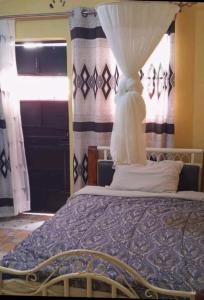 Kiminini的住宿－THE FARM BAR AND RESTAURANT，一间卧室配有一张带窗帘的床和窗户