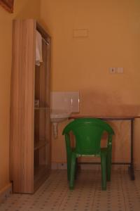 - une chaise verte dans la salle de bains pourvue d'un lavabo dans l'établissement THE FARM BAR AND RESTAURANT, à Kiminini
