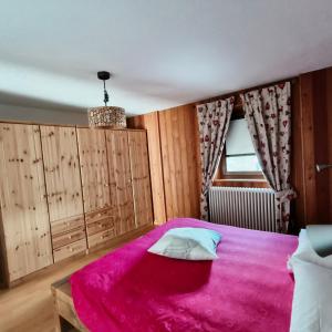 1 dormitorio con 1 cama rosa y armarios de madera en Casa Alfredo en Cogne