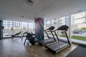 a gym with cardio equipment in a building with windows at Stella Stays Elegant Studio Dubai JVC Large Terrace in Dubai
