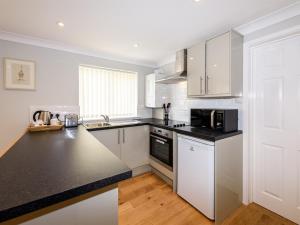 a kitchen with white cabinets and a black counter top at Vauxhall Apartments in Norwich