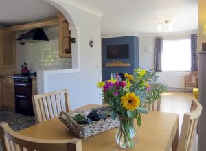 un jarrón de flores sobre una mesa en una cocina en Y Llofft Tresaith en Penbryn