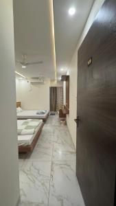 un pasillo con 2 camas y una puerta en una habitación en Hotel Prakasham, en Ujjain