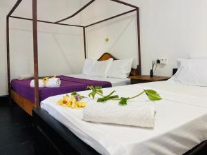 dos camas con sábanas blancas y flores. en Baywatch Arugambay, en Arugam Bay