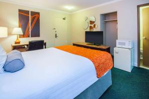 een hotelkamer met een groot bed met een oranje deken bij Howard Johnson Plaza by Wyndham Windsor in Windsor