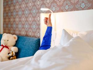 una persona acostada en la cama con su brazo sobresaliendo en Ibis Styles Regensburg en Regensburg