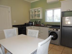 a kitchen with a table and chairs and a dishwasher at The Dunes Studio 20 in Plettenberg Bay