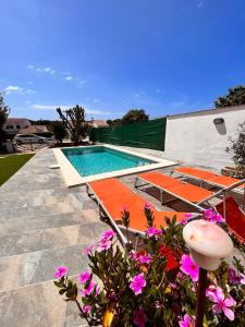 una piscina con tumbonas naranjas y flores púrpuras en Casa a pocos minutos de la playa de Cala Galdana, en Cala Galdana