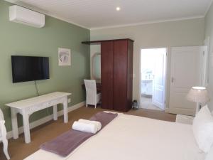 a bedroom with a bed and a desk and a television at The Dunes Studio 20 in Plettenberg Bay