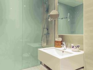 a bathroom with a sink and a glass shower at Mercure Hotel Koeln Belfortstrasse in Cologne