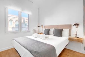 - une chambre blanche avec un grand lit et une fenêtre dans l'établissement Hogar Lujoso Centro Zaragoza, à Saragosse