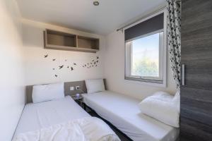 2 camas en una habitación pequeña con ventana en Mobil-home, en Les Mathes