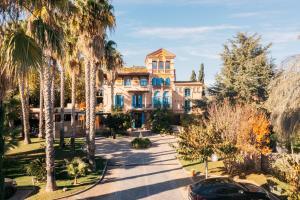 une grande maison avec des palmiers en face de celle-ci dans l'établissement Hotel Boutique Mas Passamaner, à La Selva del Camp