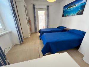 2 blaue Betten in einem Zimmer mit Fenster in der Unterkunft Villa Franca in Grado