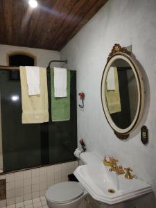 a bathroom with a toilet and a sink and a mirror at Antiquário & Pousada da Matriz in Tiradentes