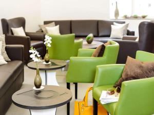 un salon avec des chaises vertes, des tables et des canapés dans l'établissement Ibis Styles Trier City, à Trèves