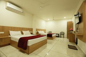 ein Hotelzimmer mit zwei Betten und einem Flachbildfernseher in der Unterkunft Slice of Heaven in Mundakāyam