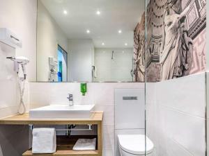 a bathroom with a sink and a toilet at Ibis Styles Trier City in Trier