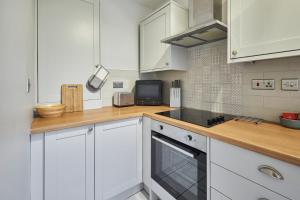 een keuken met witte kasten en een fornuis met oven bij Host & Stay - Dodds Lane in Alnwick