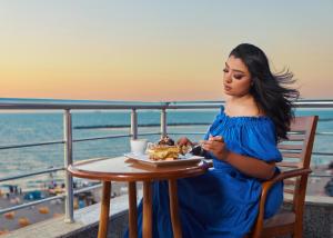 a woman sitting at a table with a plate of food at El Mena Grand in ‘Izbat al Burj