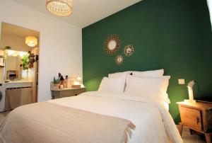 Un dormitorio con una cama blanca con una pared verde. en Cosy appartement entre vignes et garrigue avec piscine, en Péret