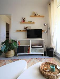 ein Wohnzimmer mit einem weißen Entertainment-Center mit einem Flachbild-TV in der Unterkunft Cosy appartement entre vignes et garrigue avec piscine in Péret