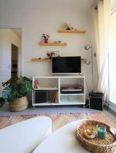 una sala de estar con un centro de entretenimiento blanco con TV de pantalla plana en Cosy appartement entre vignes et garrigue avec piscine, en Péret