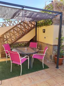 a patio with pink chairs and a table and a pergola at Acogedor apartamento loft in Alhaurín de la Torre