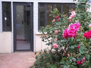 um arbusto florido com rosas rosas à frente de uma porta em Beau T3 avec jardin hyper centre proche gare em Angers